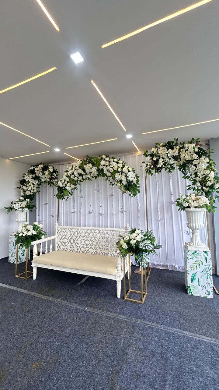 White floral stage with bench seating for celebrations