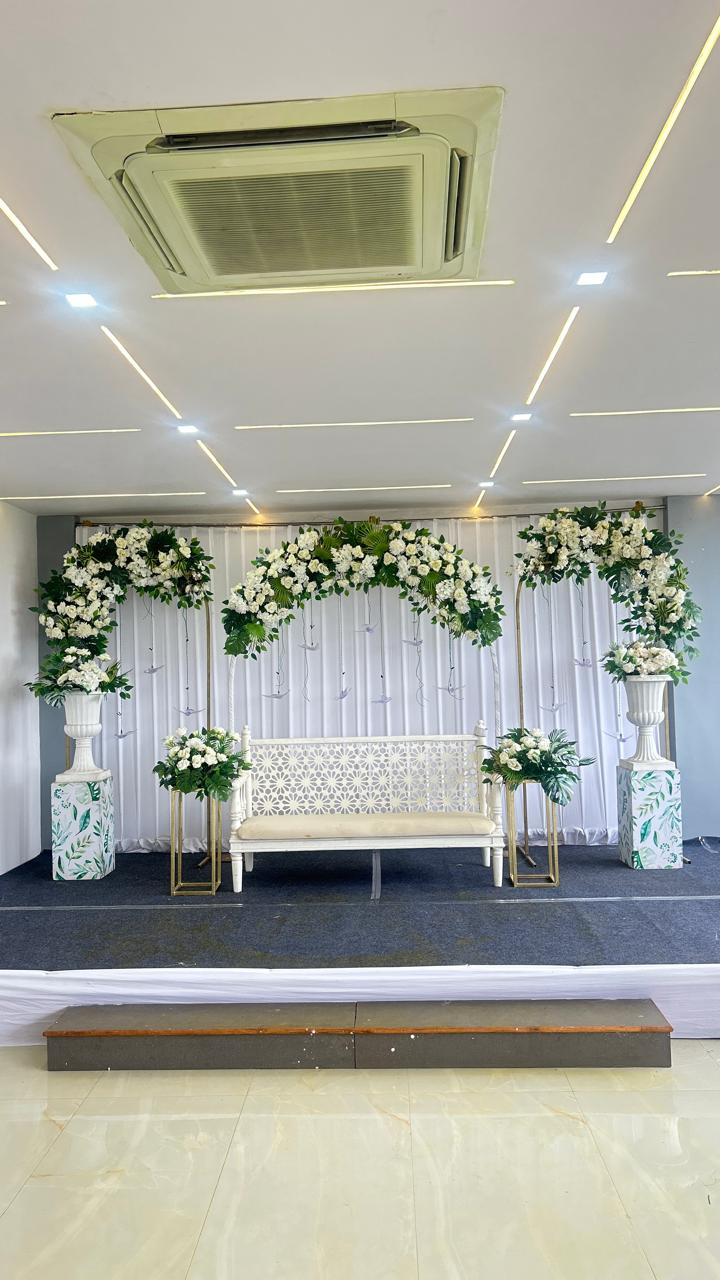 Clean white floral ceremony stage with bench seating