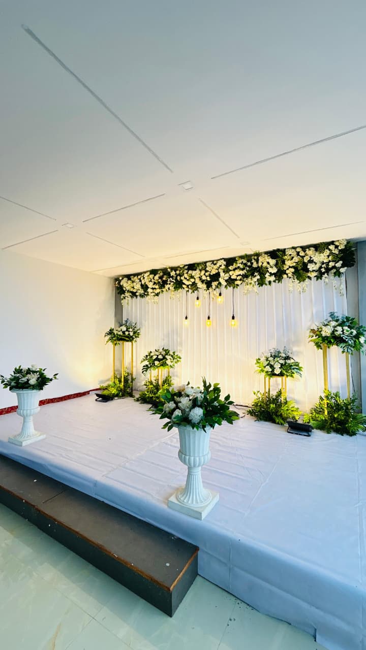 White floral stage setup with pedestal arrangements